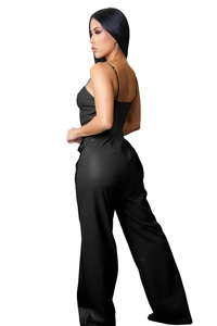 Detail of black faux leather jumpsuit featuring slim straps and an open back design
