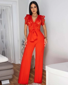 Detail of red sleeveless jumpsuit with deep V-neck lace patchwork and waist bow decoration