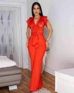 Detail view of red sleeveless jumpsuit featuring elegant lace V-neck and tied bow waist belt