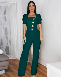 Detail of dark green jumpsuit showing square neckline and four embossed gold buttons