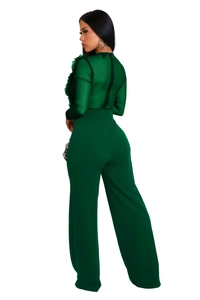 Detail of dark green jumpsuit with sheer mesh sleeves and elegant ruffled shoulders