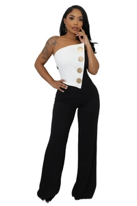 Detail view of monochrome jumpsuit showing asymmetric neckline and gold buttons