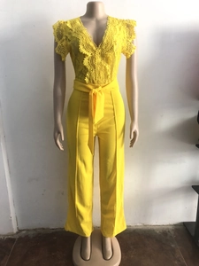 Detailed view of yellow jumpsuit featuring delicate lace patterns and V-neckline ruffles
