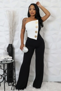 Detail of black and white jumpsuit featuring gold buttons and one-shoulder bodice