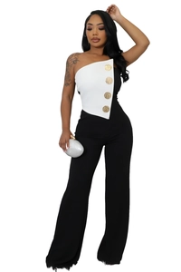 Detail of black and white tube jumpsuit featuring four large gold decorative buttons