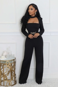 Detail of elegant black long-sleeve jumpsuit featuring cutout neckline and gold chain belt