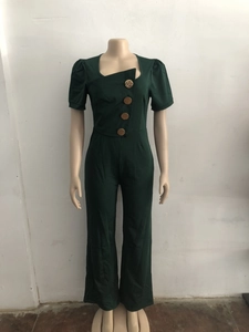 Detail of dark green short sleeve jumpsuit featuring square neck and large gold buttons