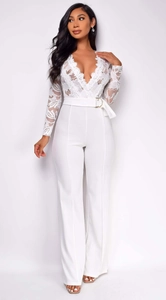 Detail of white lace jumpsuit featuring sheer floral sleeves and a high-waisted belted design
