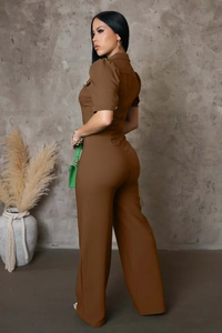 Side view of dark brown jumpsuit with puff sleeves and wide legs on a model