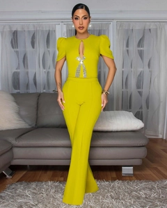 Detail of lime yellow jumpsuit featuring puff sleeves and sparkling rhinestone bow decor