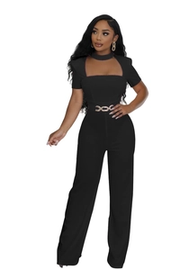 Détail de la combinaison noire élégante avec découpe au décolleté et ceinture chaîne dorée