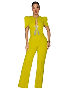 Detailed view of rhinestone bow and cutout neckline on mustard green short sleeve jumpsuit