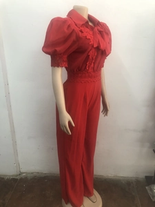 Makroaufnahme von roten Spitzendetails und Schleife am Jumpsuit mit Puffärmeln