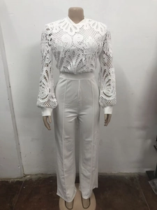 Close-up of intricate white lace embroidery and pleated high-waisted wide-leg trousers