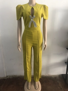 Detail of mustard yellow jumpsuit featuring puff sleeves and a rhinestone bow buckle