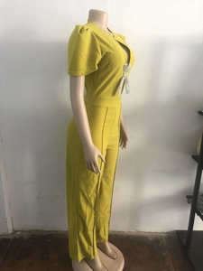 Close-up of V-neck mustard yellow jumpsuit with a sparkling rhinestone bow detail