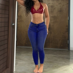 Détail d'un jean slim bleu foncé avec un haut licou en latex rouge à effet brillant