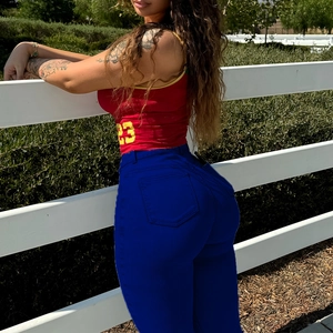 Détail d'un jean skinny taille haute bleu foncé porté avec un maillot rouge en plein air