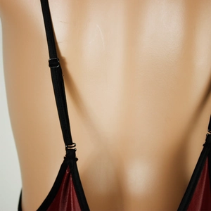 Detail of adjustable black straps and glossy dark red satin fabric on a bodysuit