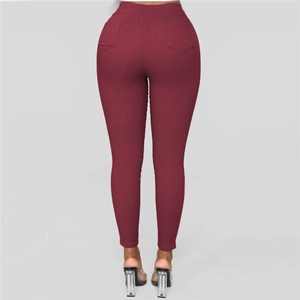 Detail view of burgundy high-waisted slim-fit pants with rear pockets and push-up effect