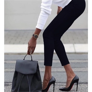 Detail of slim fit black pencil pants styled with pointed heels on urban street background