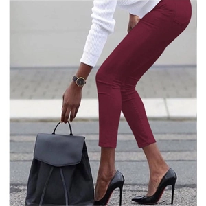 Chic burgundy skinny pencil trousers for women paired with black heels in urban setting