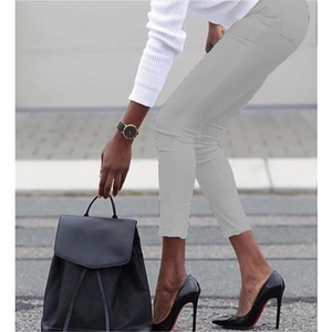 Women's light grey slim fit pencil pants paired with high heels in a city street view
