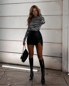 Detail of high waisted black PU leather mini skirt with side slit and zebra print top