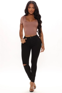 Detail of high waist ripped black skinny jeans with distressed knee cutout design