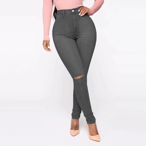 Detail of high waisted dark grey skinny jeans featuring a distressed ripped knee design