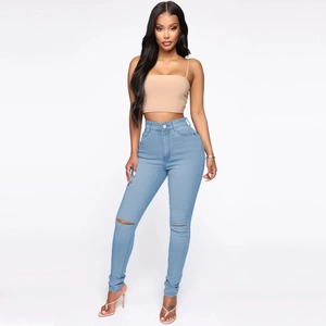 Detail view of high waist skinny jeans in light blue featuring distressed knee cutouts
