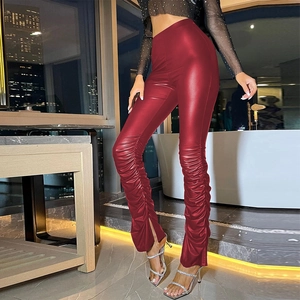 Detail view of dark red high-waisted PU leather pants with ruched legs and ankle slits