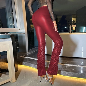 Detail shot of red shiny stacked leggings with ankle side slits and pleated design