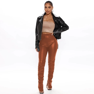 Close-up of rust-colored faux leather stacked pants with side slits and pleat detail