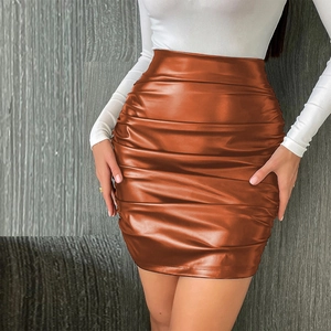 Détail d'une mini-jupe en similicuir caramel à taille haute avec fronces horizontales