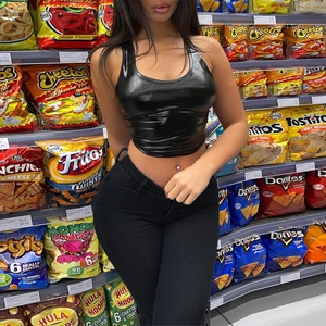 Detail of high-waisted black skinny jeans paired with a glossy PU sleeveless crop top