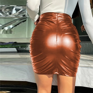 Détail de la mini-jupe en similicuir marron caramel avec une texture plissée froncée latérale