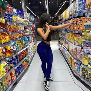 Detail of high waisted stretchy blue skinny jeans on model in casual supermarket setting