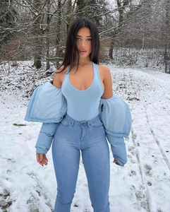Ensemble trois pièces avec doudoune bleu clair et jean ajusté dans un décor de neige