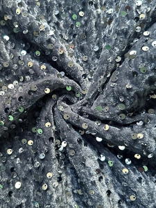 Close-up of sparkling silver sequins on premium grey velvet fabric texture detail