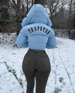 Rear view of light blue padded jacket featuring Trapstar gothic print against snowy forest