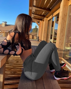 Détail d'un jean skinny taille haute gris foncé avec un crop top noir en extérieur