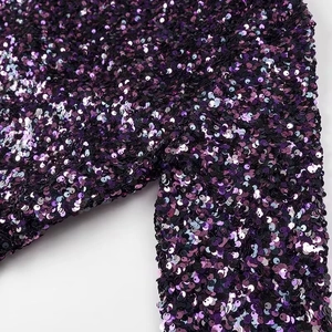 Gros plan de paillettes violettes denses sur une robe chatoyante à la texture métallique