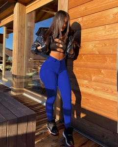 Gros plan d'un jean skinny bleu roi vif porté avec une veste noire brillante courte