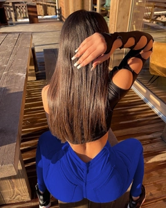 Détail du jean bleu roi à effet push-up et haut noir ajouré sur terrasse en bois