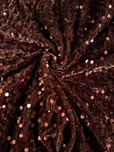 Close-up of sparkling sequins on burgundy velvet fabric with elegant draped texture