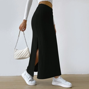 Detail view of the side slit and vertical ribbed texture on a black knit maxi skirt