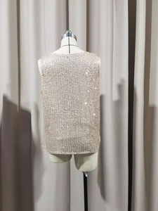 Detailed macro shot of champagne gold sequins on an elegant V-neck sleeveless top