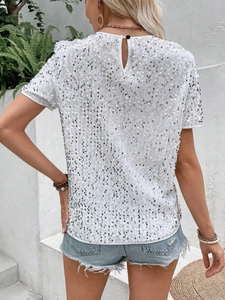 Detail of white sequin top featuring back keyhole cutout and elegant silver shimmering texture