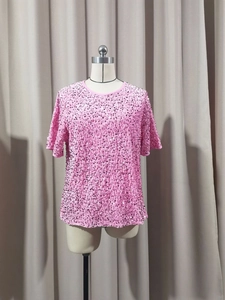 Detailed view of pink sequin texture and crew neck collar on a loose fit women's top